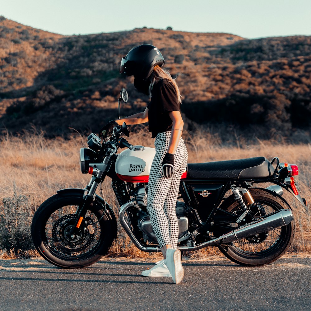 woman in black and white dress riding on black motorcycle during daytime