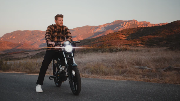 Side view of a sleek Voltrider electric dirt bike kicking up dirt on a rugged trail at sunset.