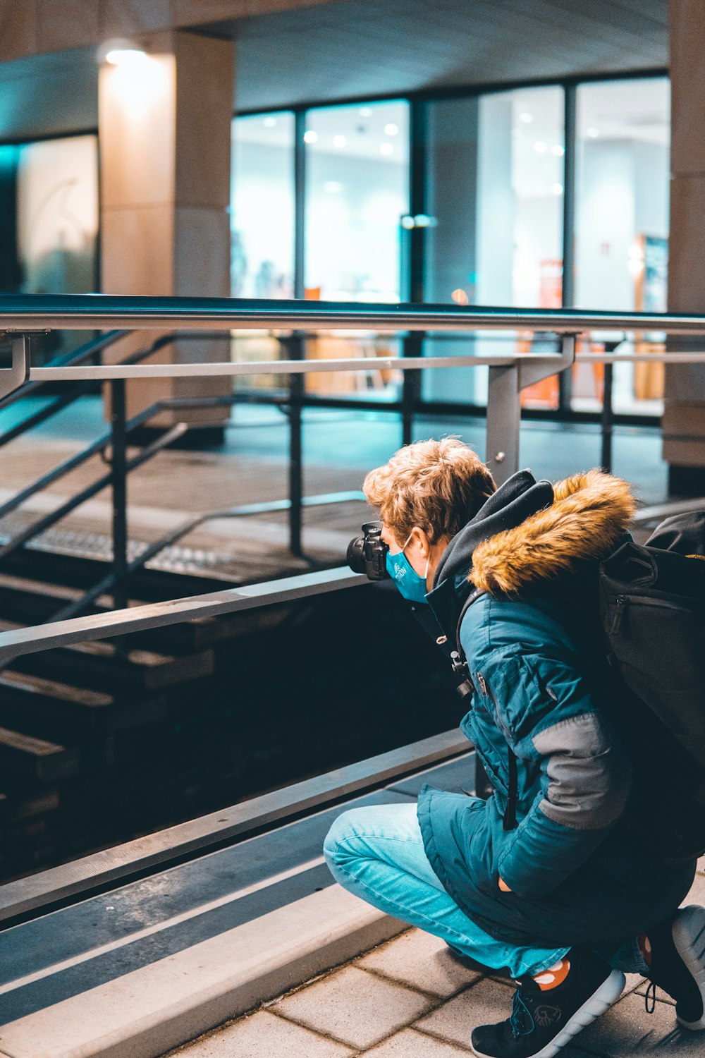 woman in blue denim jacket and blue denim jeans sitting on black metal railings