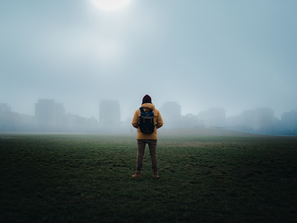 woman in black shirt and black shorts standing on green grass field during foggy weather