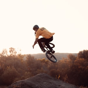 man in brown shirt riding bicycle on brown rock during daytime