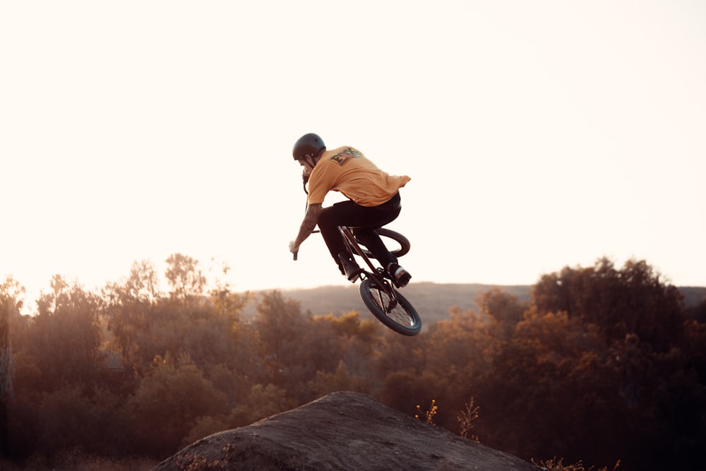 Hombre en camisa marrón montando en bicicleta en roca marrón durante el día