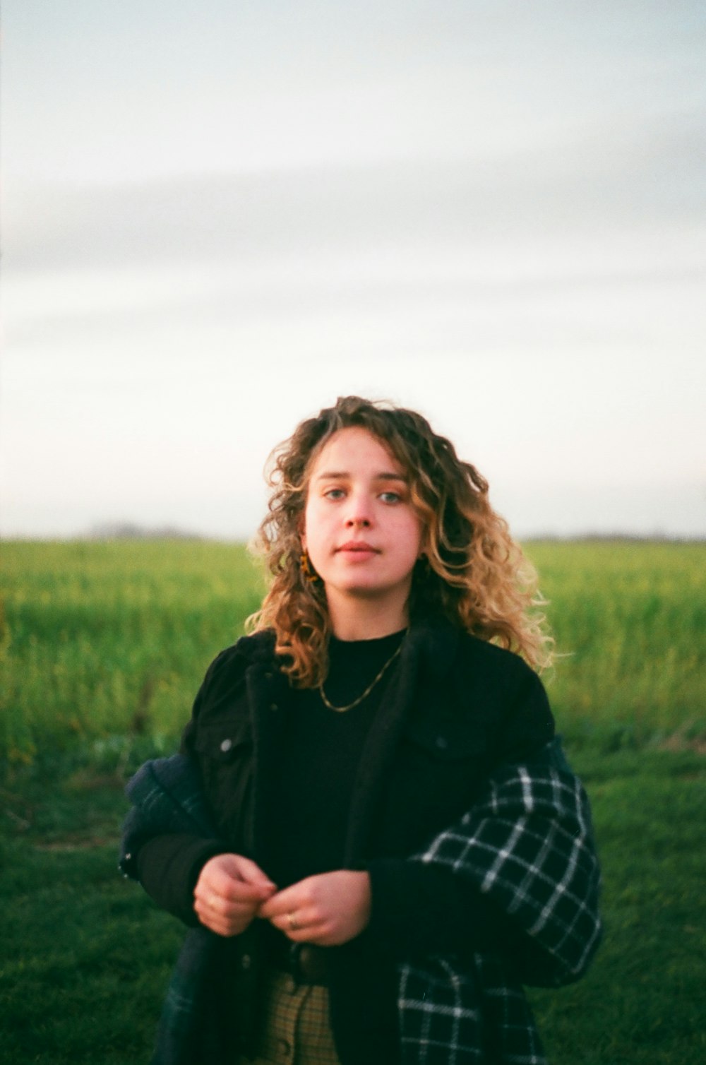 woman in black jacket standing on green grass field during daytime