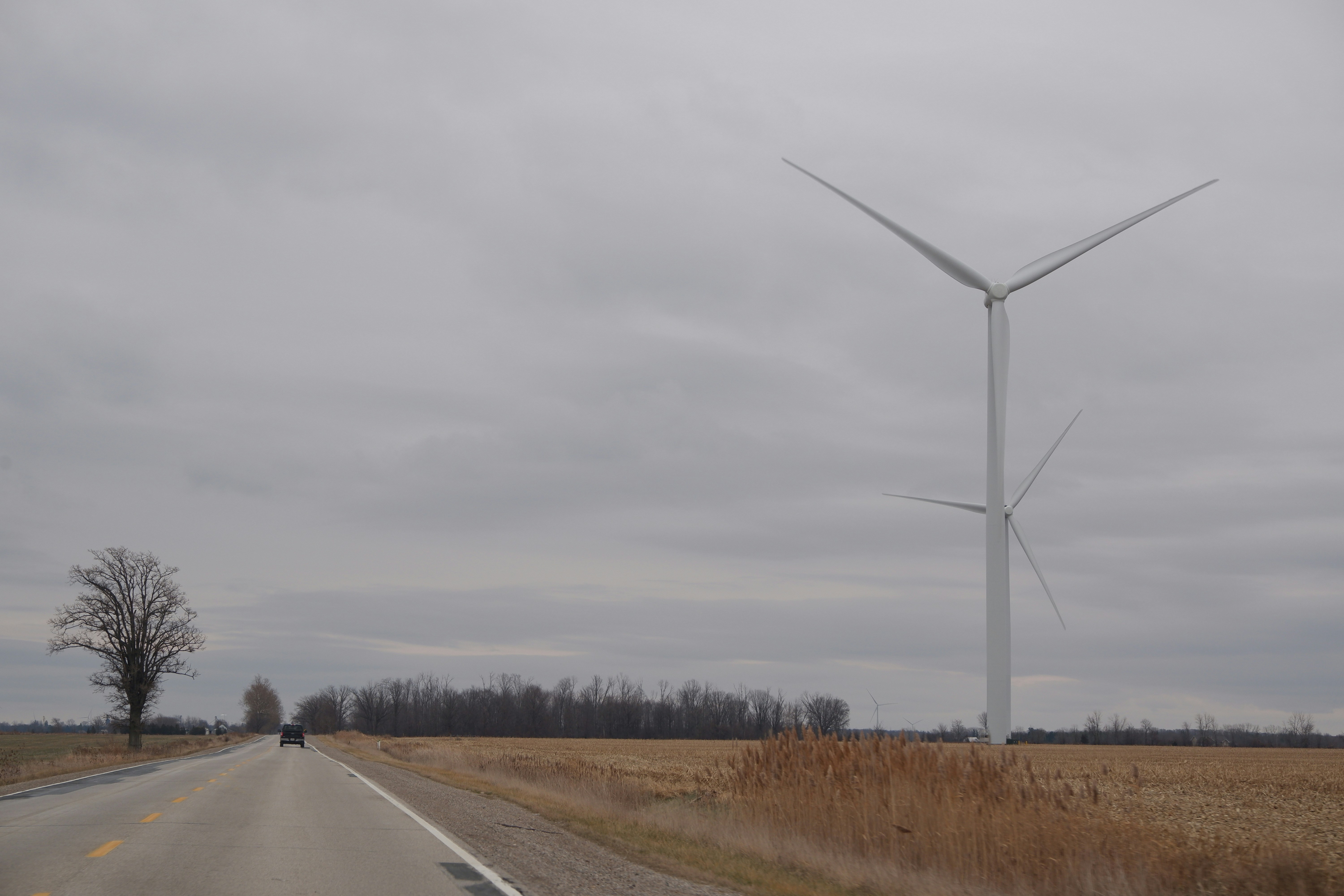 white wind turbine on brown grass field under white clouds during daytime