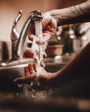 person holding white powder on stainless steel faucet