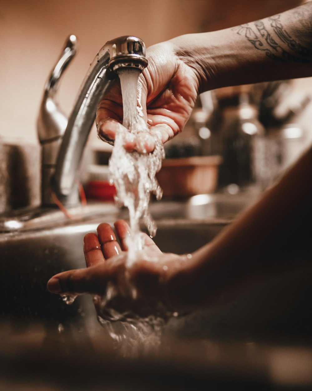 person holding white powder on stainless steel faucet