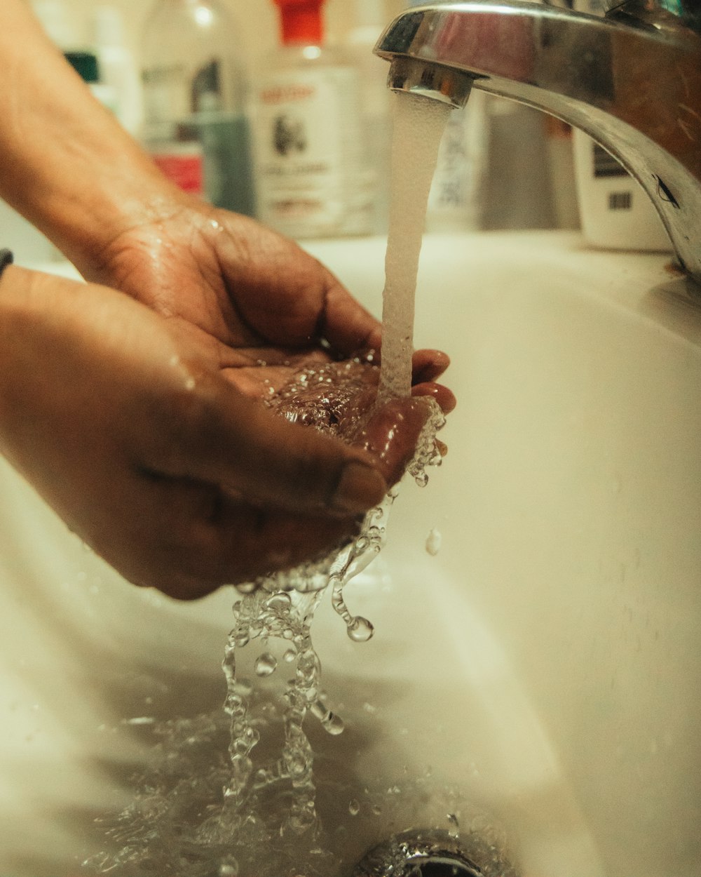 person washing red liquid on sink