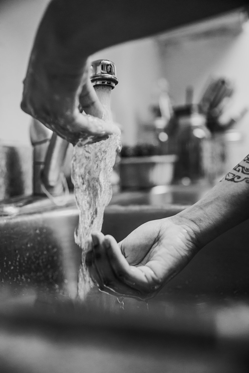grayscale photo of person pouring water on persons hand