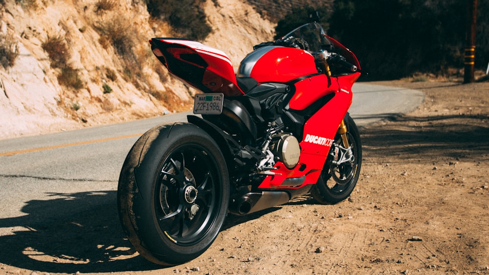 red and black sports bike on gray sand during daytime