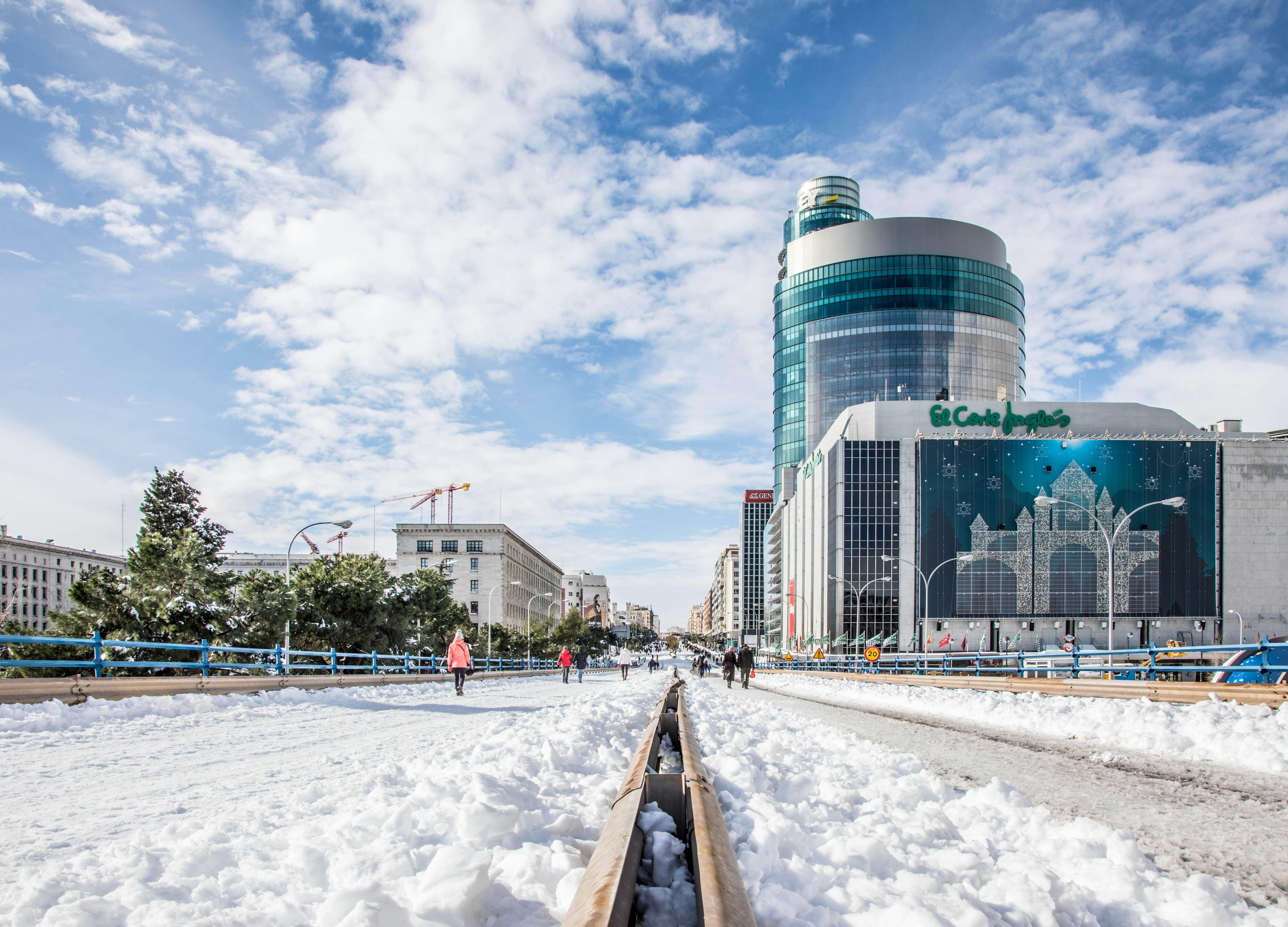 people walking on snow covered field near city buildings during daytime