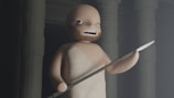A stylized animated character with a simple facial expression stands holding a spear in one hand. The background features large, shadowy columns, creating an ancient or mystical atmosphere. The character has a bald head and a beard, wearing a basic one-shoulder garment.