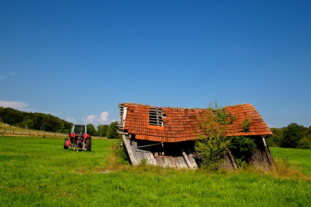 Braunes Holzhaus auf grünem Rasenfeld unter blauem Himmel tagsüber