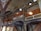 An intricately designed interior with ornate wooden and column details, featuring decorative patterns and arches. The architecture includes painted motifs, geometric designs, and carved elements.