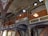 An intricately designed interior with ornate wooden and column details, featuring decorative patterns and arches. The architecture includes painted motifs, geometric designs, and carved elements.