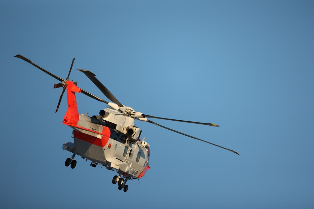 red and white helicopter flying in the sky