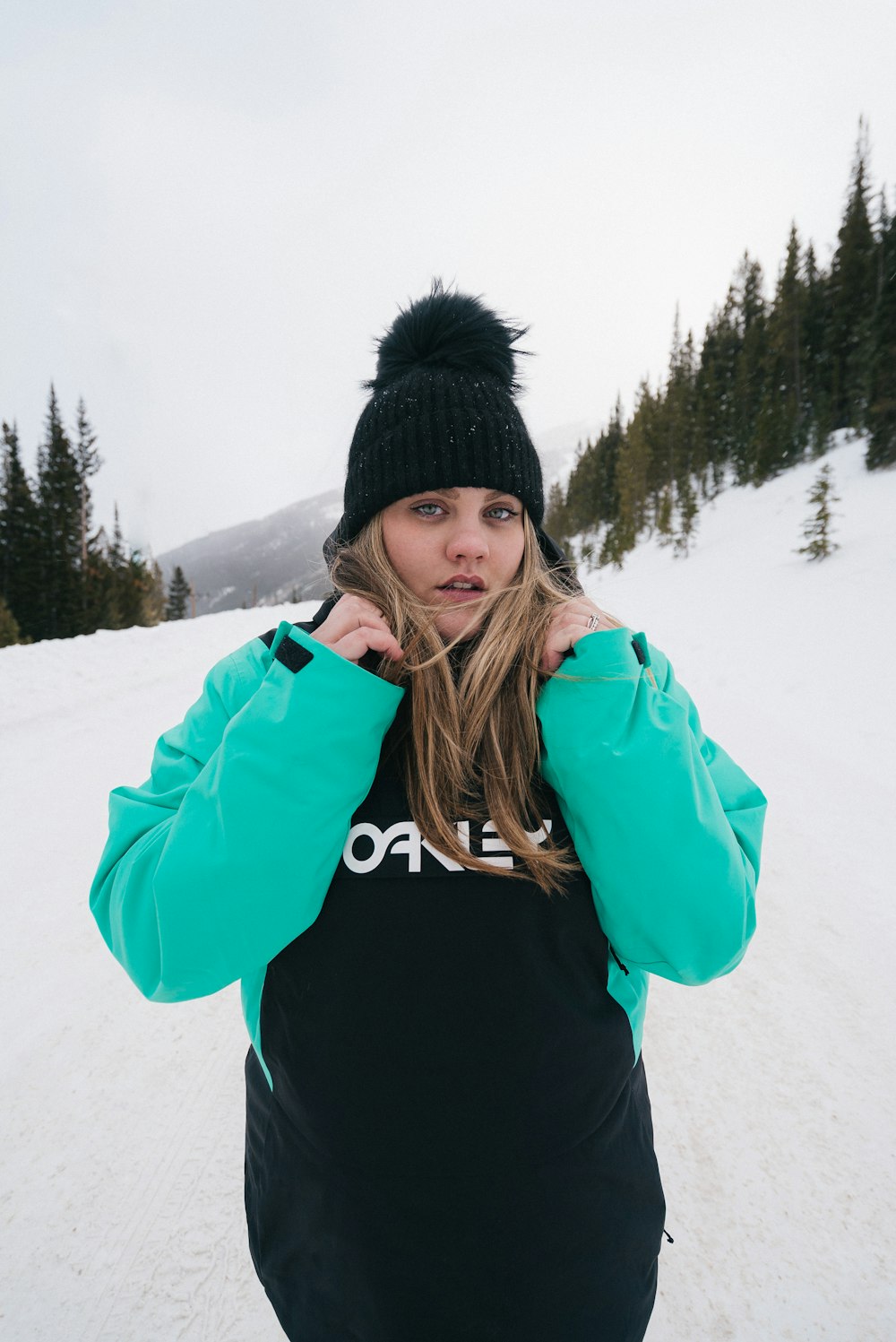 woman in blue jacket and black knit cap standing on snow covered ground during daytime