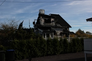 Wide shot of a home exterior showing repaired fire damage under bright daylight.