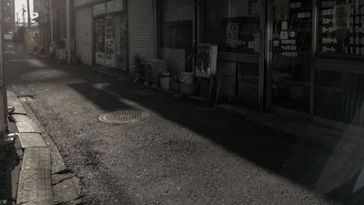 Wide shot of a downtown alley with a figure dressed in modern streetwear, shadows dancing.