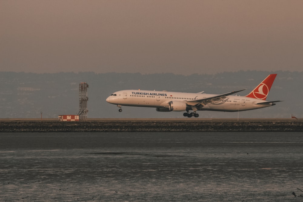 white and red passenger plane on airport during daytime