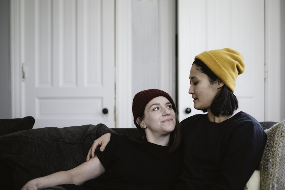 man in black sweater sitting beside woman in red knit cap