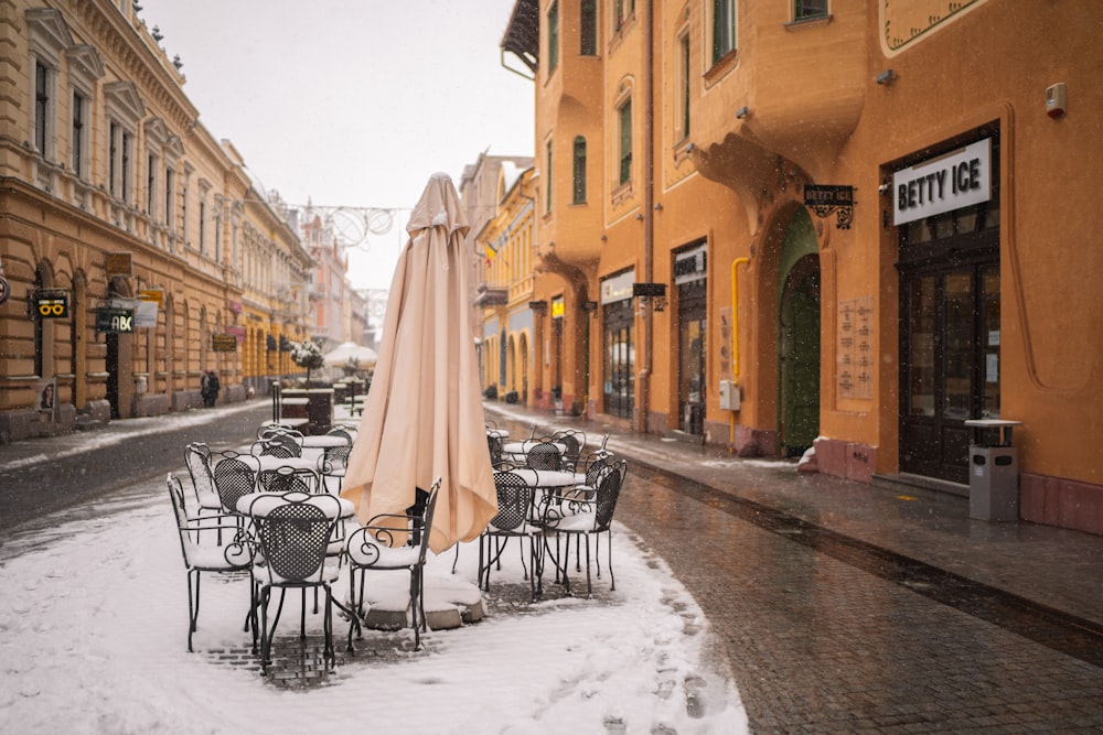white umbrella on black metal chairs on snow covered ground