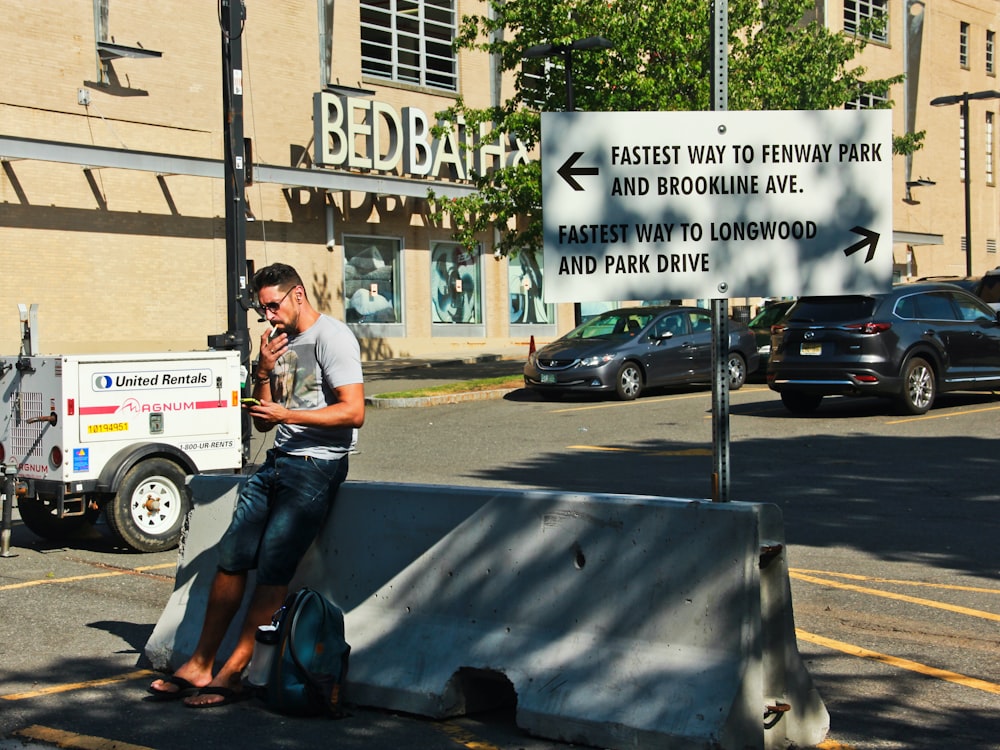 woman in white t-shirt and blue denim jeans sitting on gray concrete bench during daytime