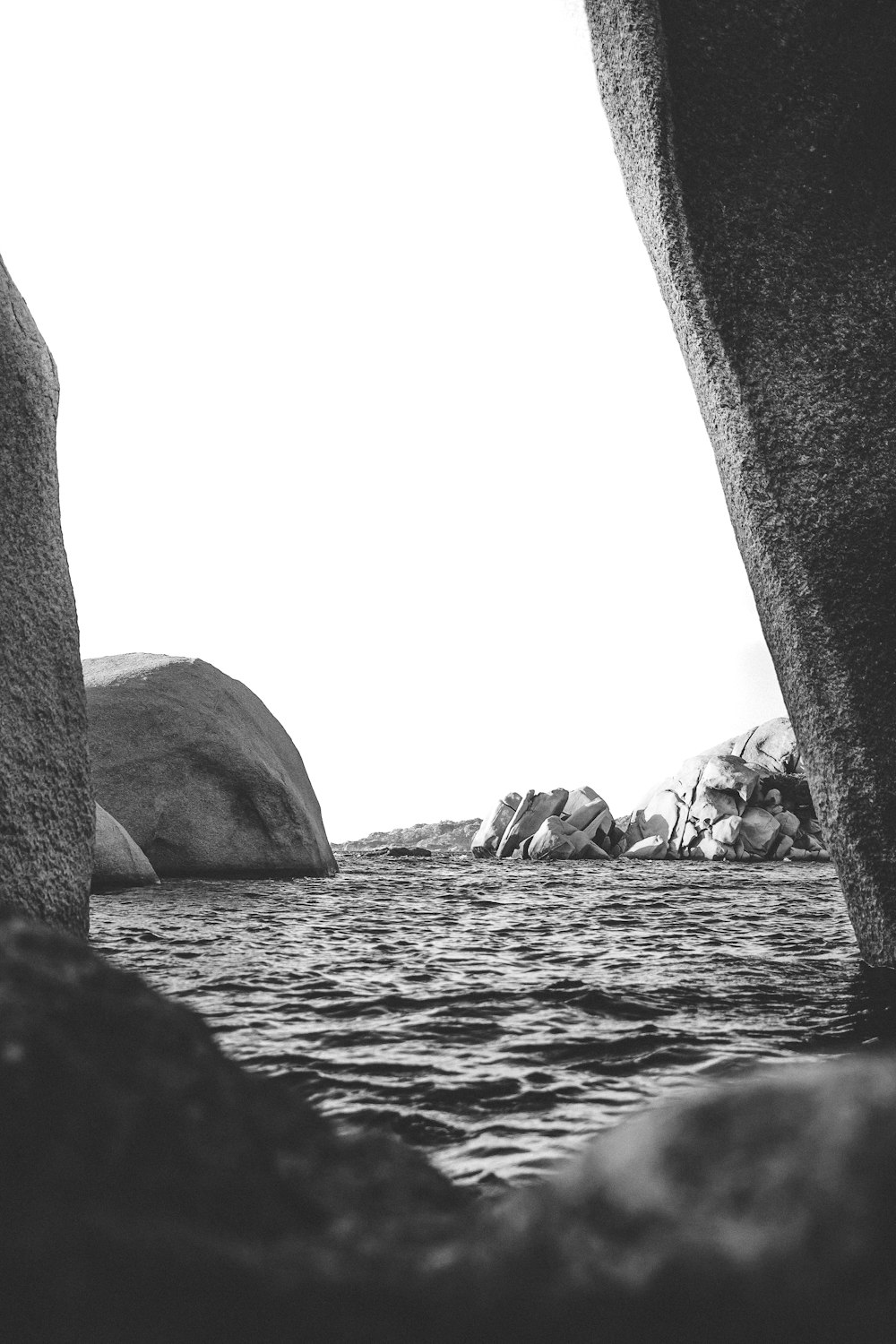 Photo en niveaux de gris de roches sur l’eau