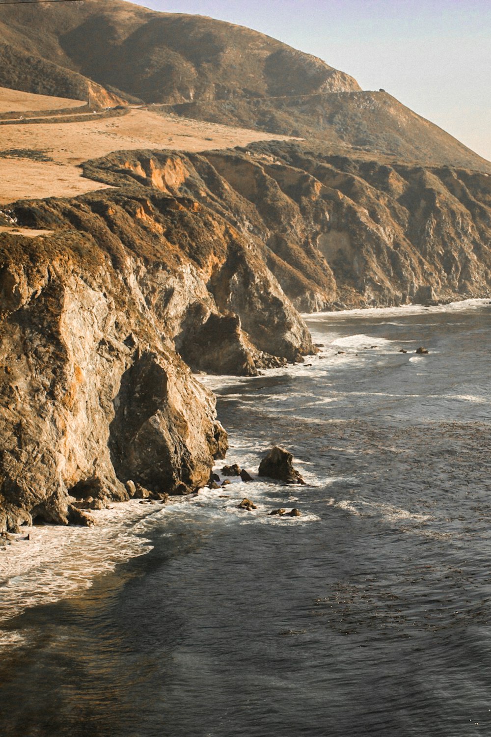 brown rock formation beside body of water during daytime