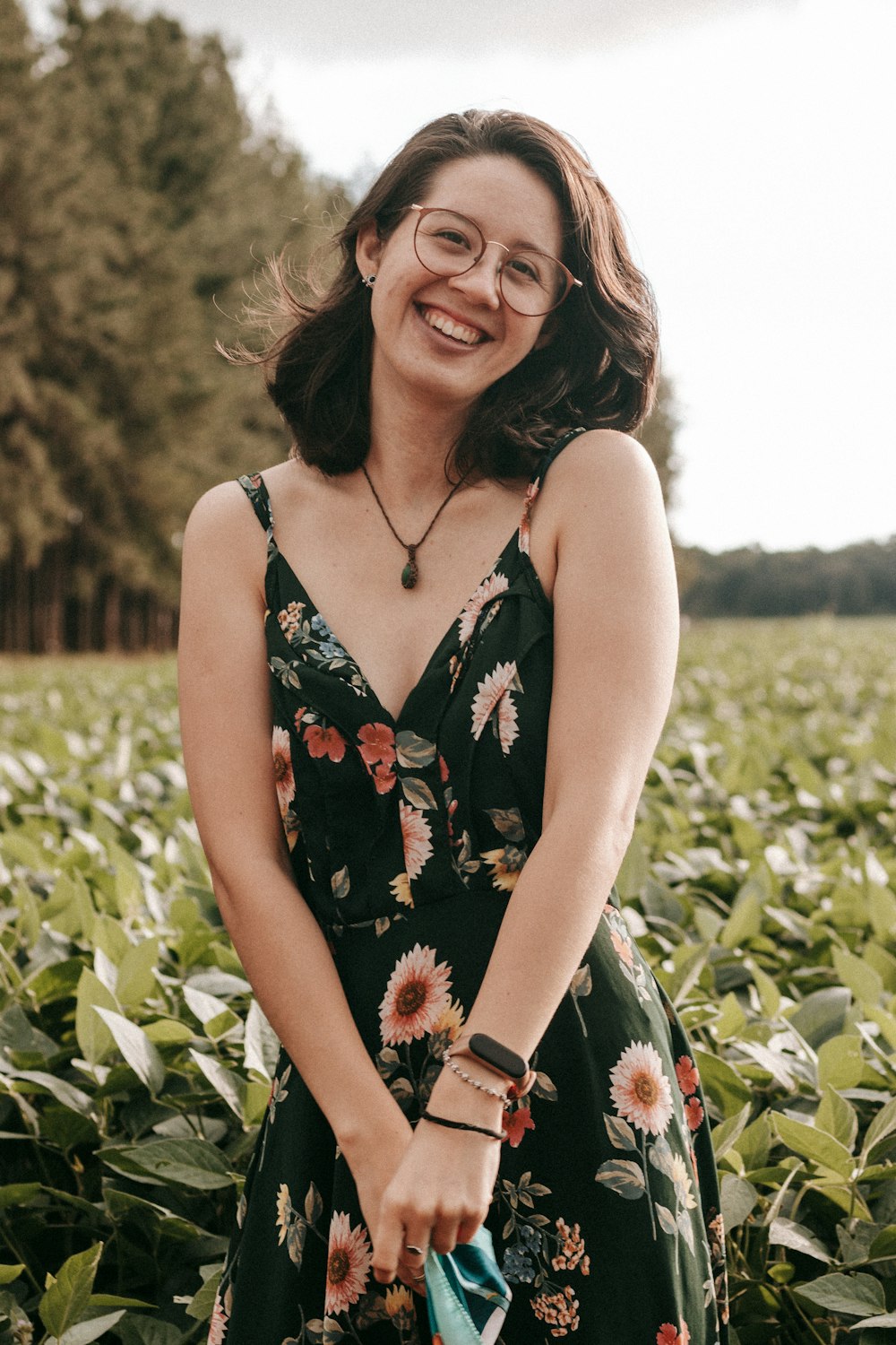 Femme en robe à bretelles spaghetti florales noires et rouges souriante