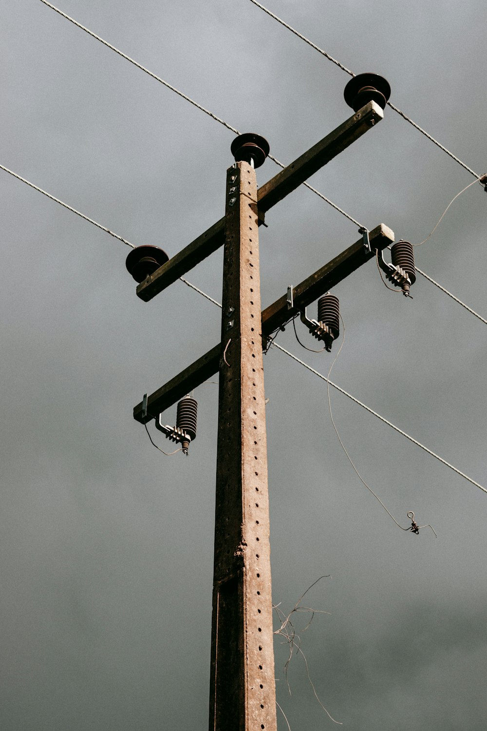 brown wooden electric post under blue sky during daytime