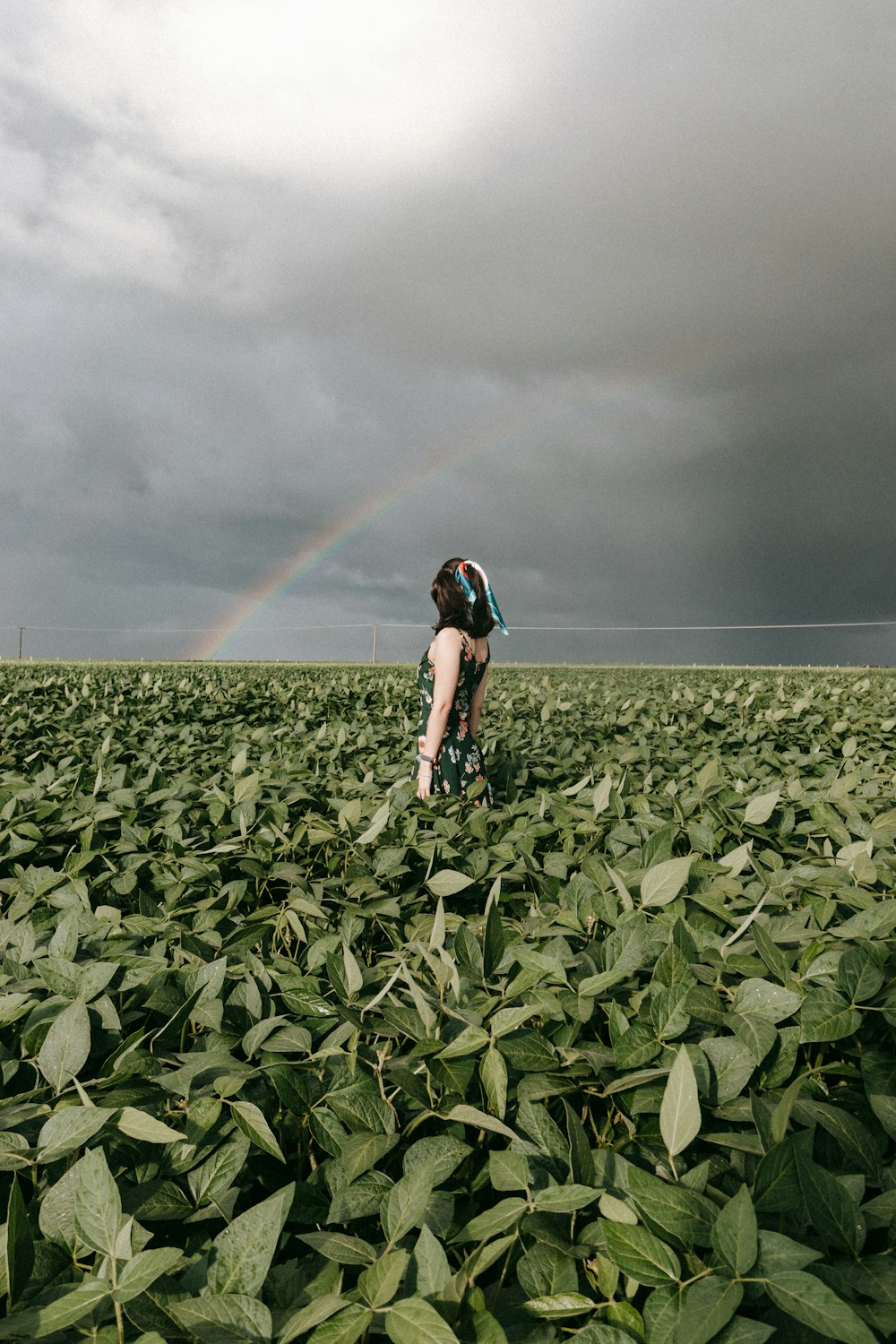 woman in black tank top and black shorts standing on green grass field under gray sky