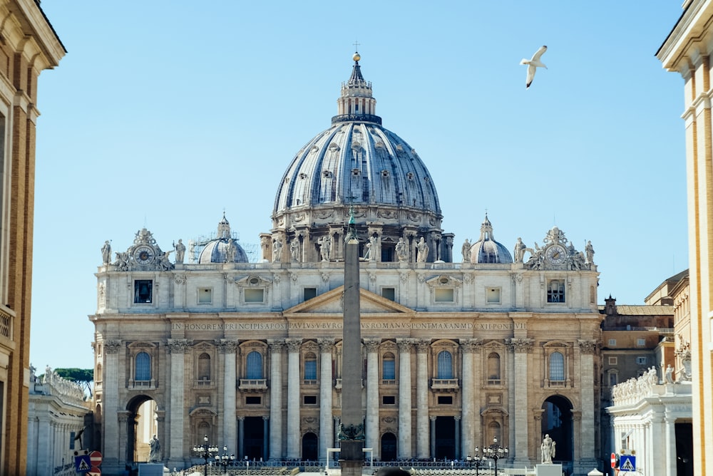 edificio in cemento bianco con bandiere in cima durante il giorno