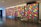A series of four large panels display a vibrant, geometric pattern composed of multicolored rectangles. The artwork is installed in a modern, spacious gallery with a reflective marble floor and recessed lighting. Each panel features a varied arrangement of colorful shapes, creating a dynamic visual rhythm.