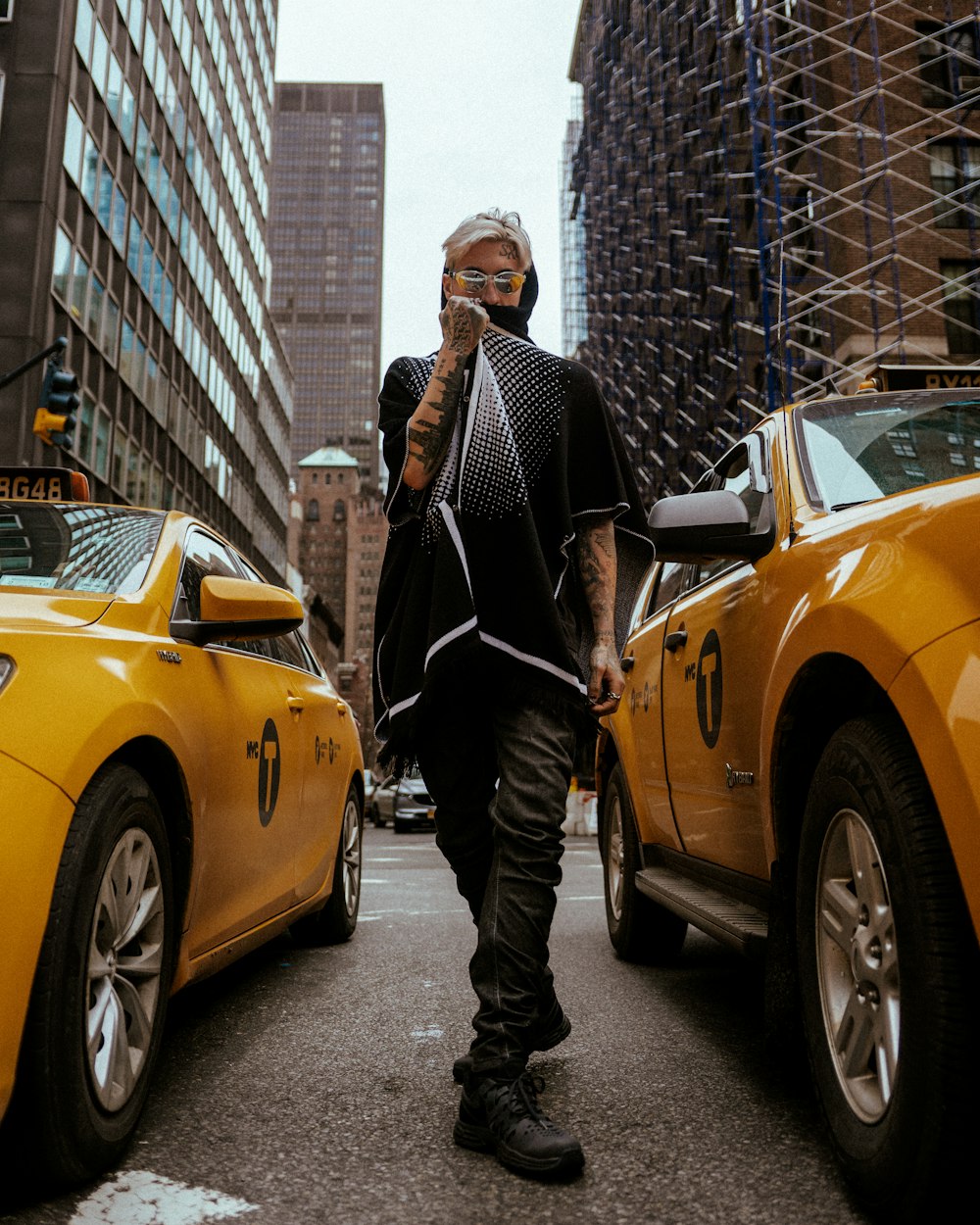 hombre con traje negro de pie junto a un coche amarillo