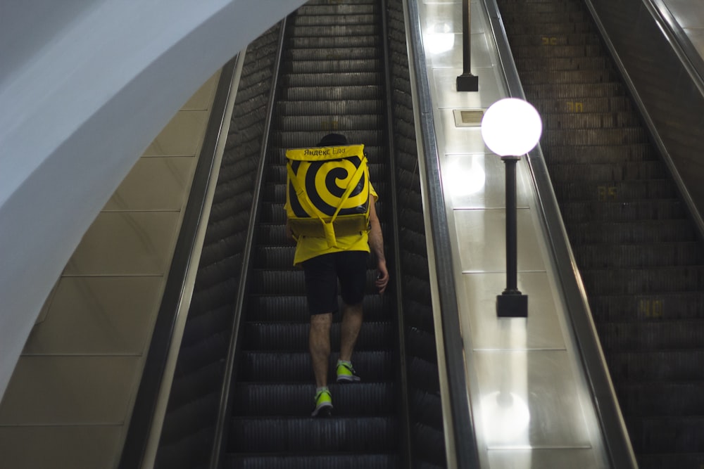 person in yellow and black batman shirt and black shorts walking on black staircase