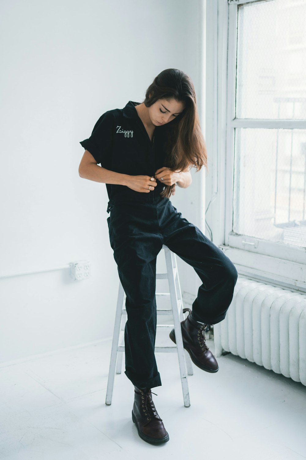 woman in black crew neck t-shirt and blue denim jeans standing beside white wall