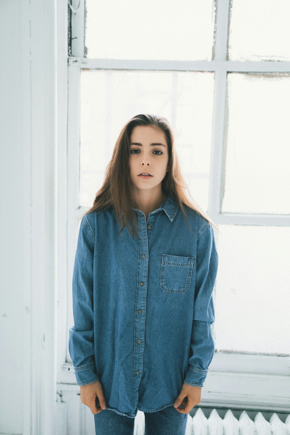 woman in blue denim jacket standing near white wooden door