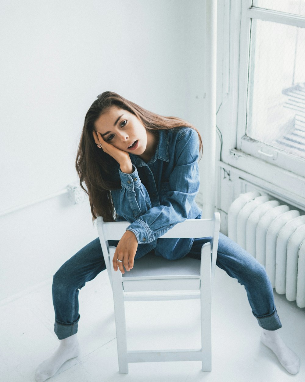 woman in blue denim jacket and blue denim jeans sitting on white wooden chair
