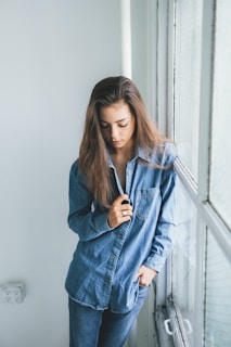 woman in blue denim jacket standing near white wall