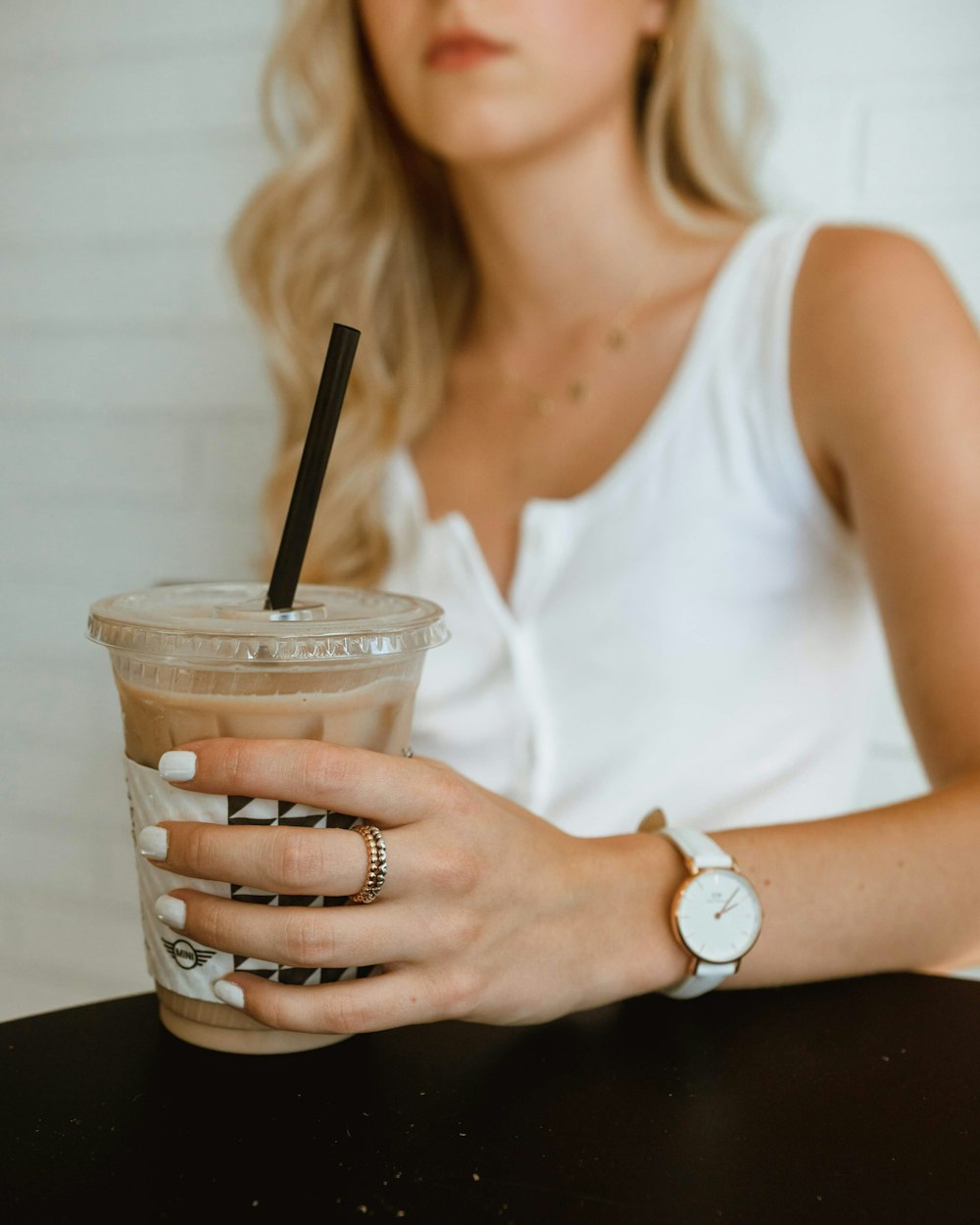 woman in white tank top holding clear plastic cup