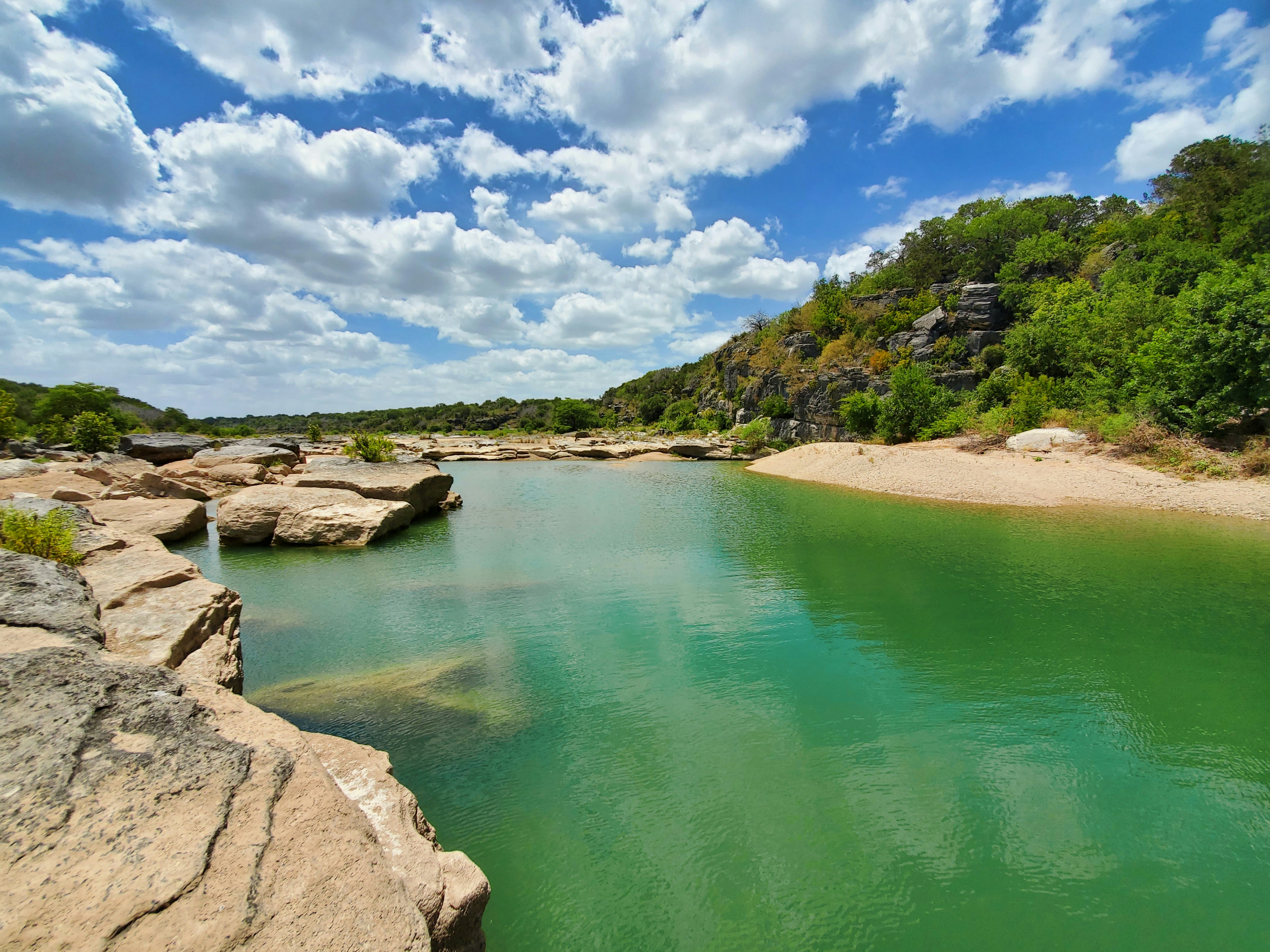 green lake surrounded by green trees under blue sky during daytime, 