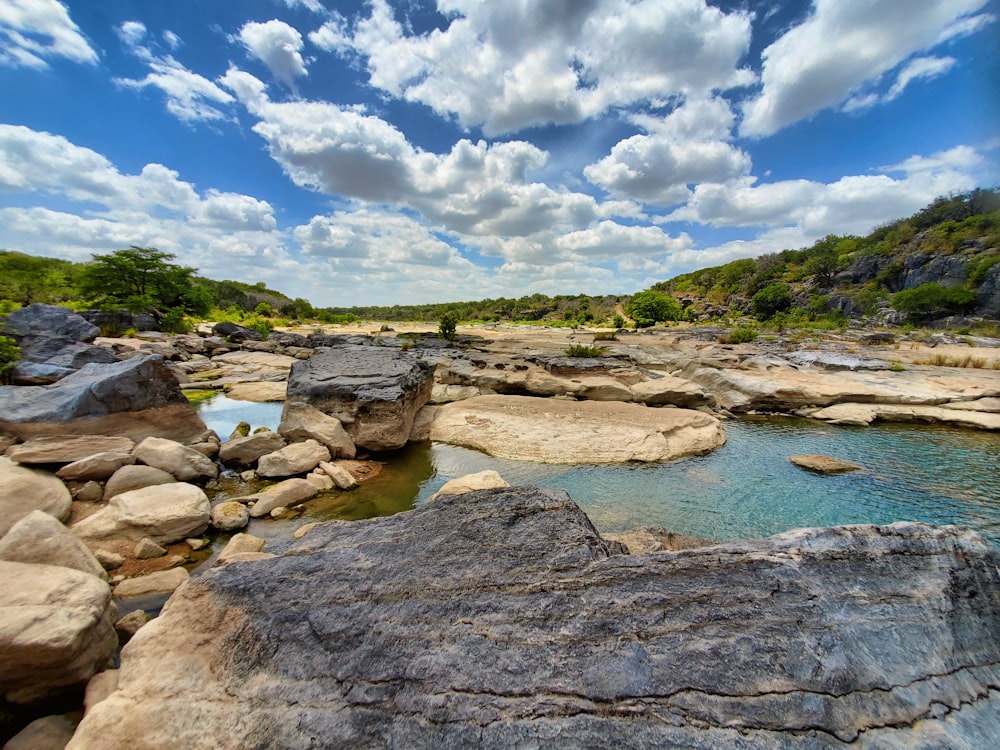 brown rocky shore under blue sky and white clouds during daytime