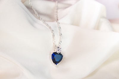 An elegant pendant featuring a deep blue lapis lazuli gem hanging against a soft fabric background.