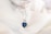 Close-up of a delicate silver necklace with a small gemstone pendant on a soft fabric background.