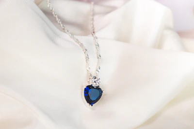Close-up of a delicate lilac gemstone pendant with engraved initials, resting on soft velvet.