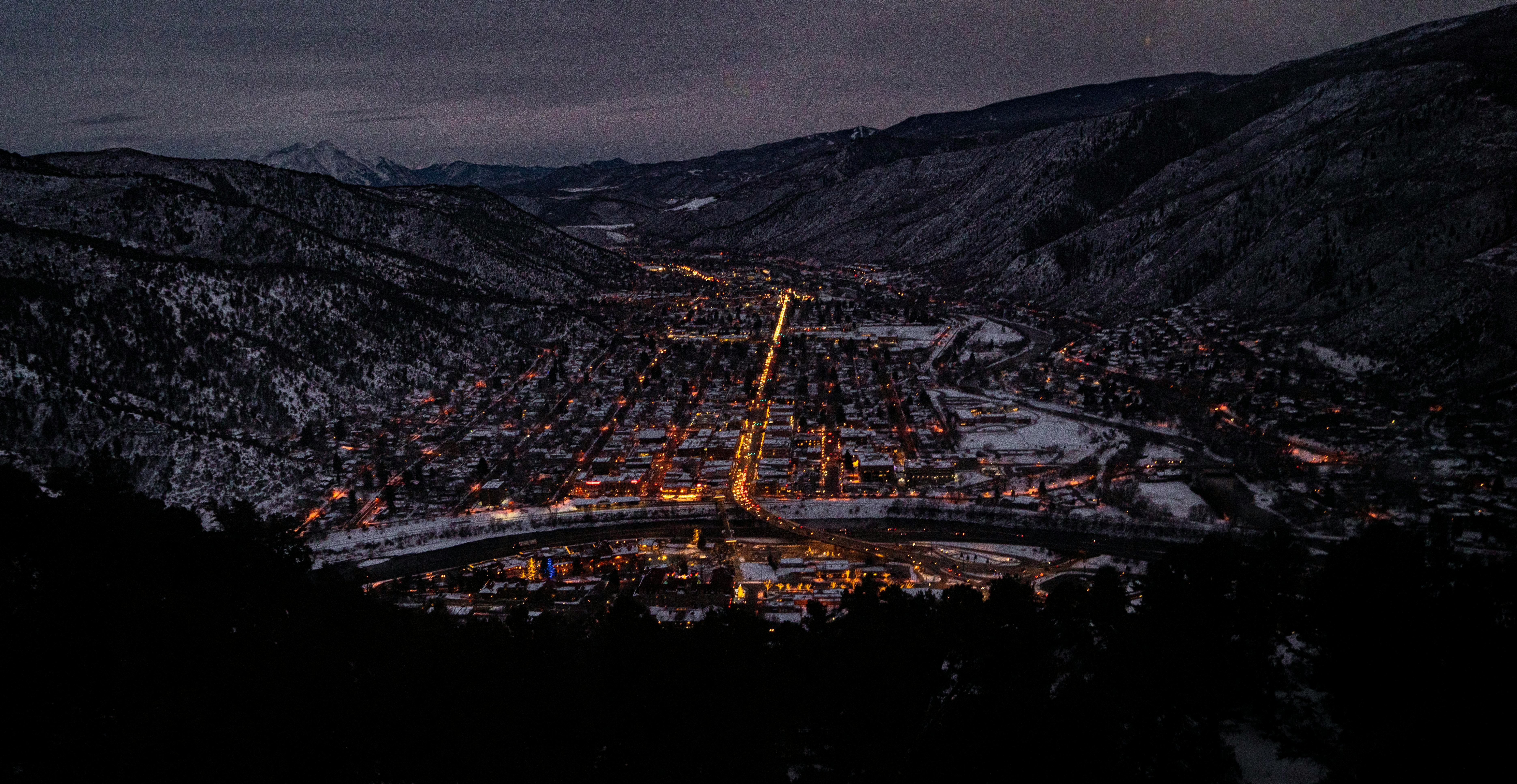 city with high rise buildings near mountain under gray sky during night time