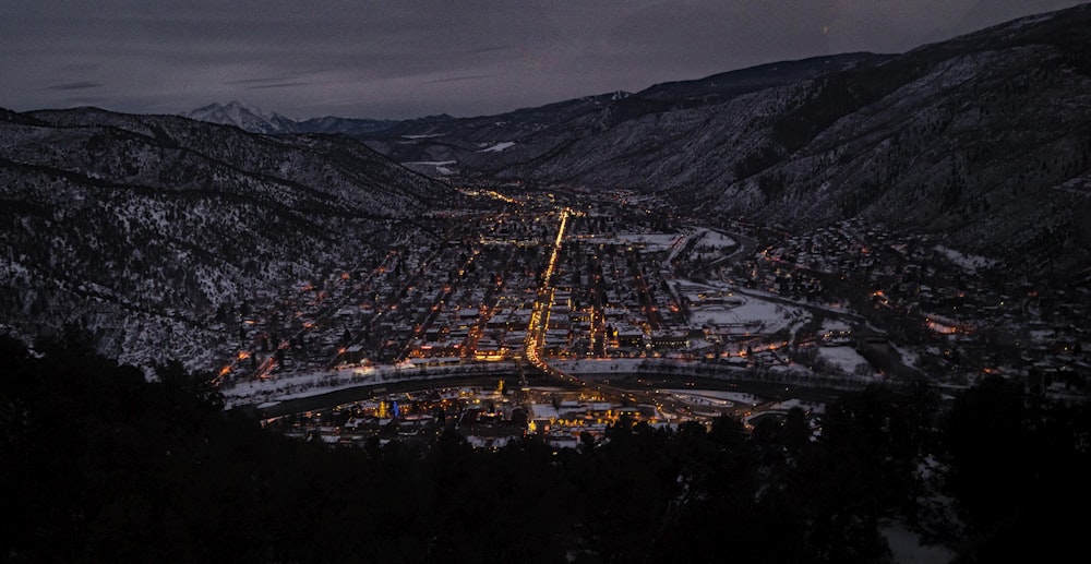 ciudad con edificios de gran altura cerca de la montaña bajo el cielo gris durante la noche