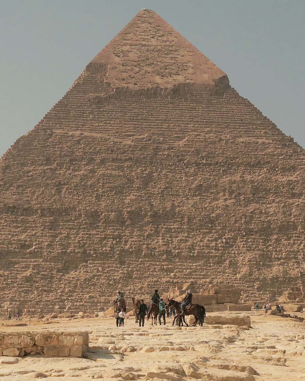 낮에 피라미드 근처의 갈색 모래 위를 걷는 사람들