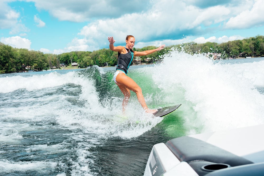 woman in black and red wetsuit surfing on water during daytime