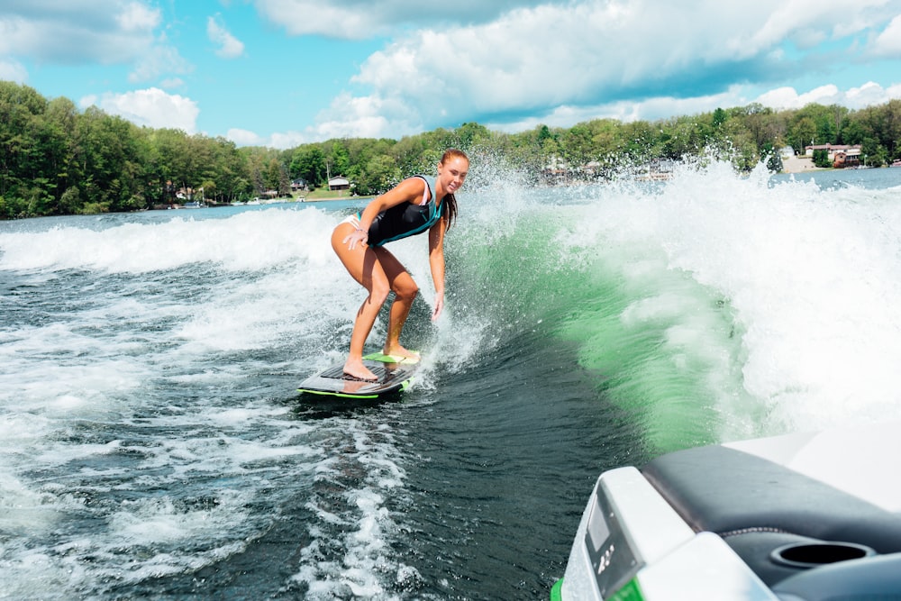 Mujer en la parte superior del bikini azul y negro surfeando en el agua durante el día